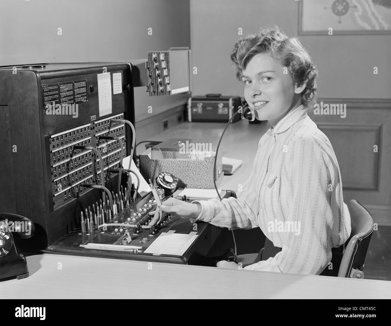 1950 SMILING WOMAN AU BUREAU TÉLÉPHONE STANDARDISTE Banque D'Images