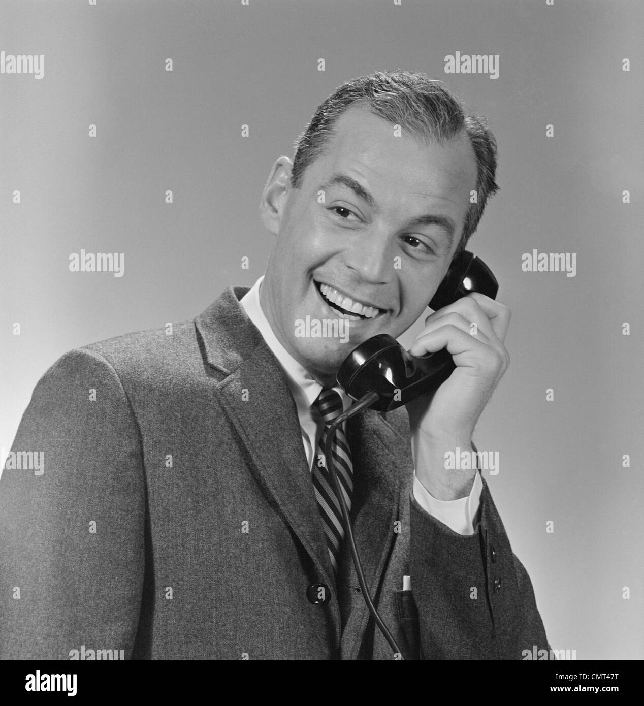 Années 1950 Années 1960 SMILING BUSINESS MAN CONVERSATION TÉLÉPHONIQUE Banque D'Images