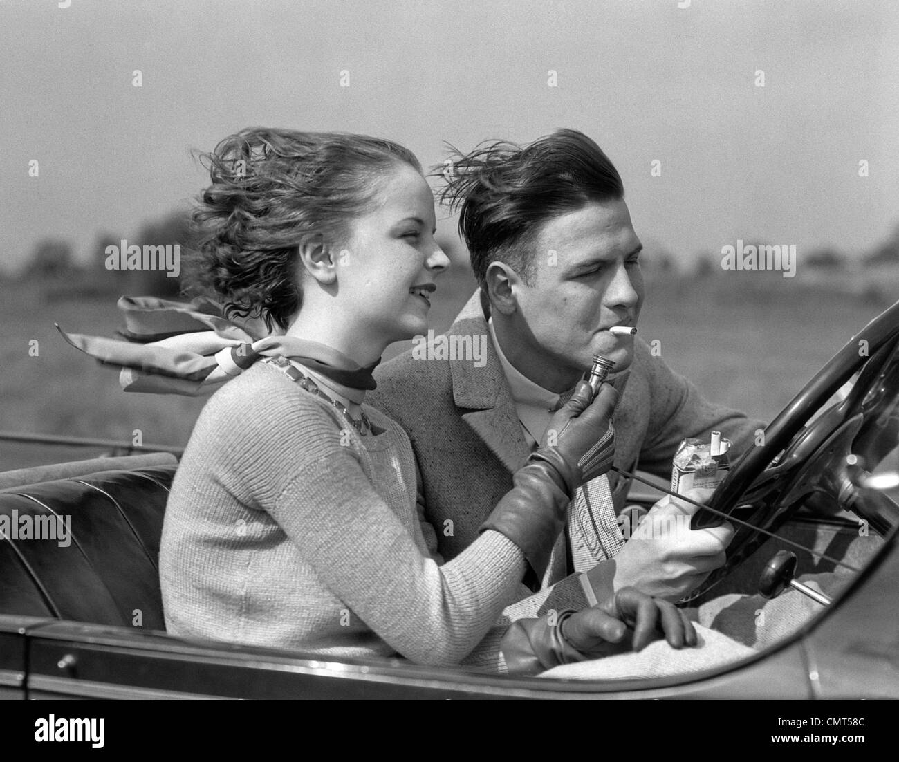 1930 MAN DRIVING CONVERTIBLE AUTOMOBILE TOUT AMIE allume sa cigarette Banque D'Images
