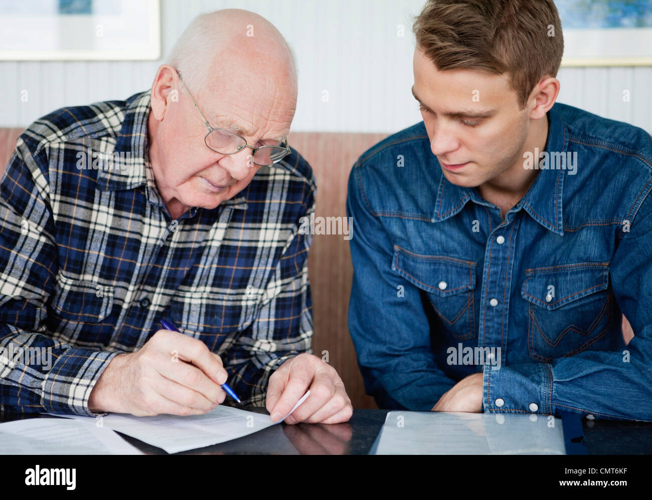 Jeune homme grand-père aide pour remplir un formulaire Banque D'Images
