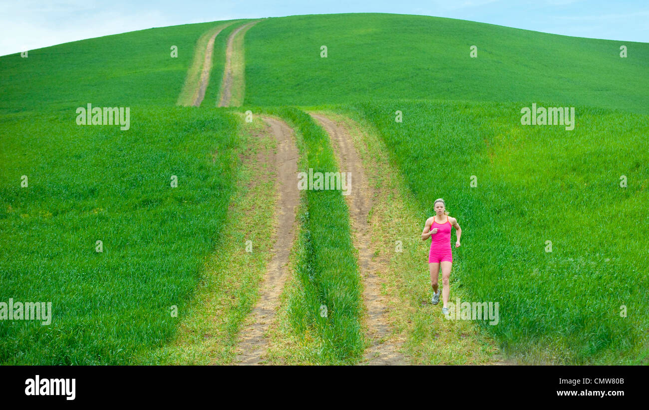 Caucasian woman running on path through field Banque D'Images