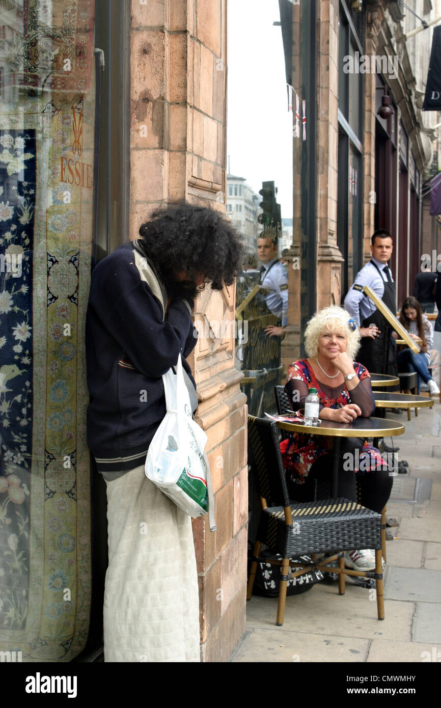 Femme au café regarder personne sans-abri, Piccadilly, Londres Banque D'Images