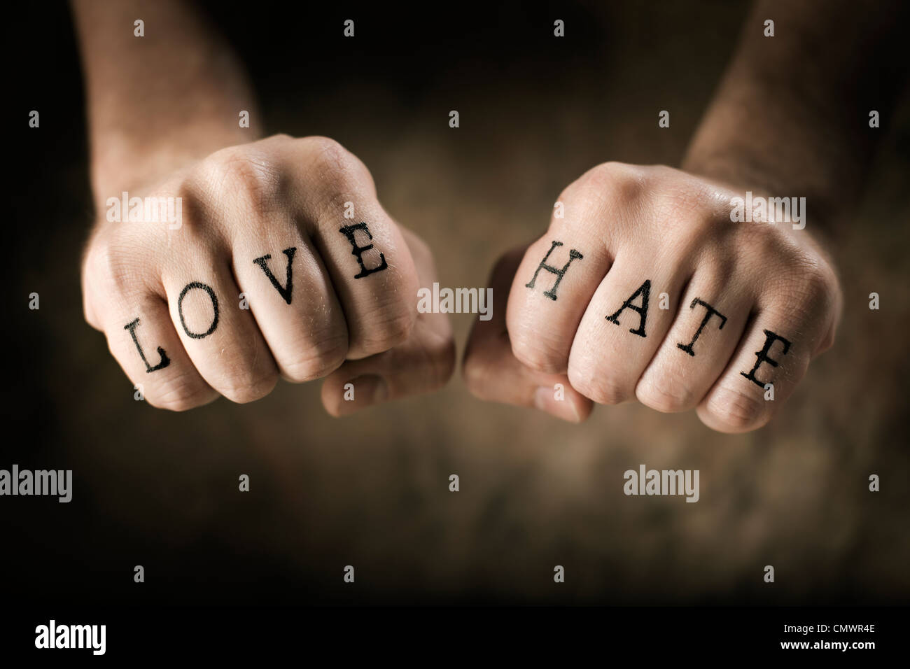 Homme avec (faux) l'amour et la haine des tatouages sur ses mains. Banque D'Images