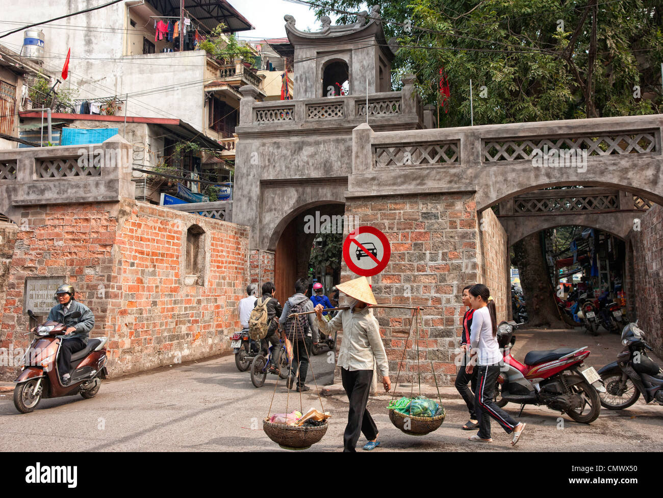 Vendeur alimentaire carry wares passé, ancienne porte de la ville et le mur à Hanoi Banque D'Images