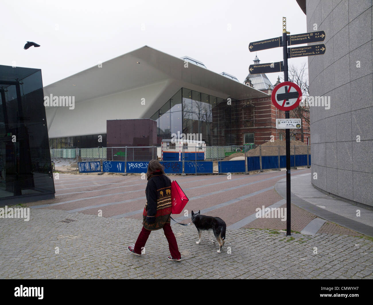 Femme avec son chien marcher sur le Museumplein square en face de la nouvelle controverse Stedelijk Museum à Amsterdam d'extension Banque D'Images