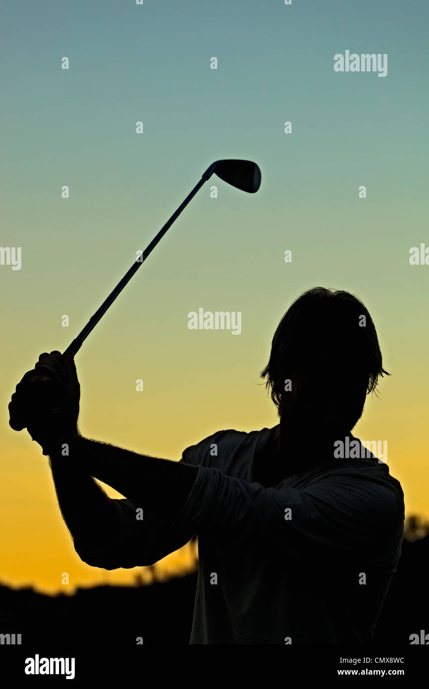Golfeur découpé sur le coucher du soleil en milieu d'élan avec fer à repasser. Banque D'Images