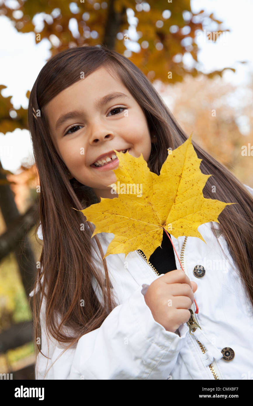 Allemagne, Huglfing, Girl holding leaf, smiling, portrait Banque D'Images