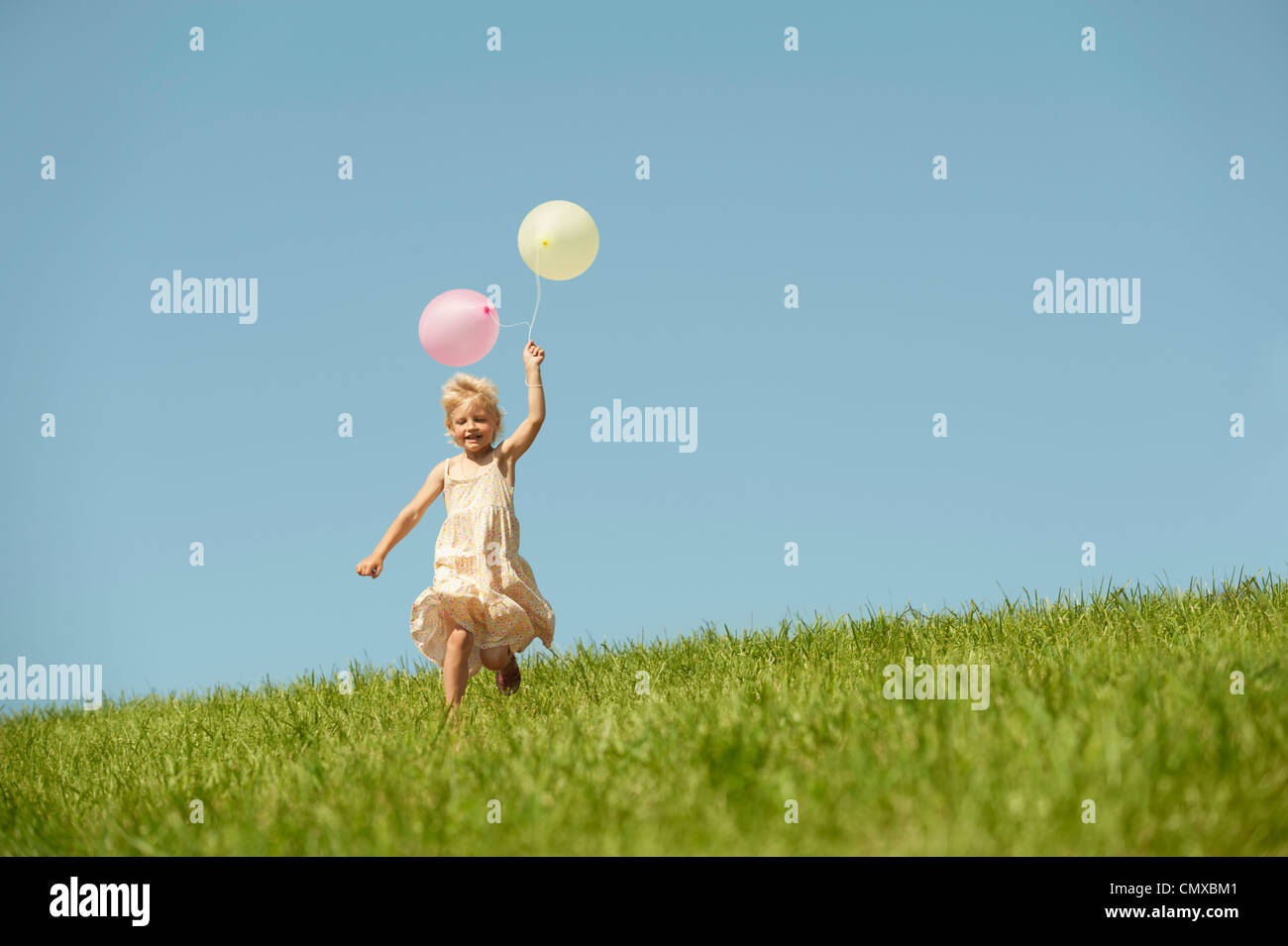 Allemagne, Bavière, fille courir avec des ballons dans l'herbe Banque D'Images