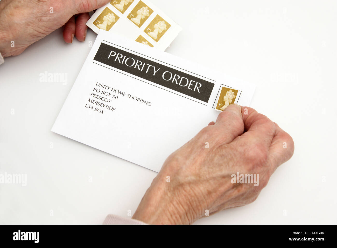 Femme âgée mettant une 1ère classe premier timbre sur une enveloppe prêt pour l'affichage (augmentations de prix 30 Avril 2012 Banque D'Images