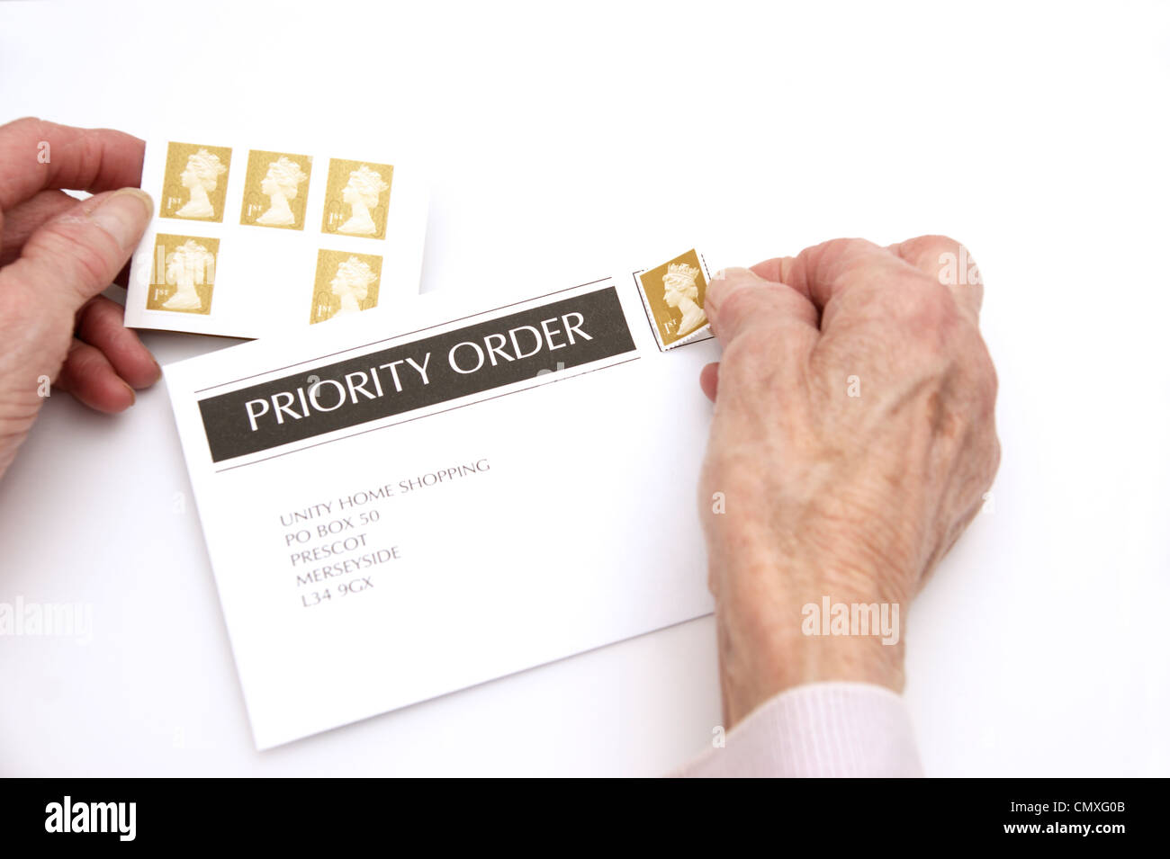 Femme âgée mettant une 1ère classe premier timbre sur une enveloppe prêt pour l'affichage (augmentations de prix 30 Avril 2012 Banque D'Images