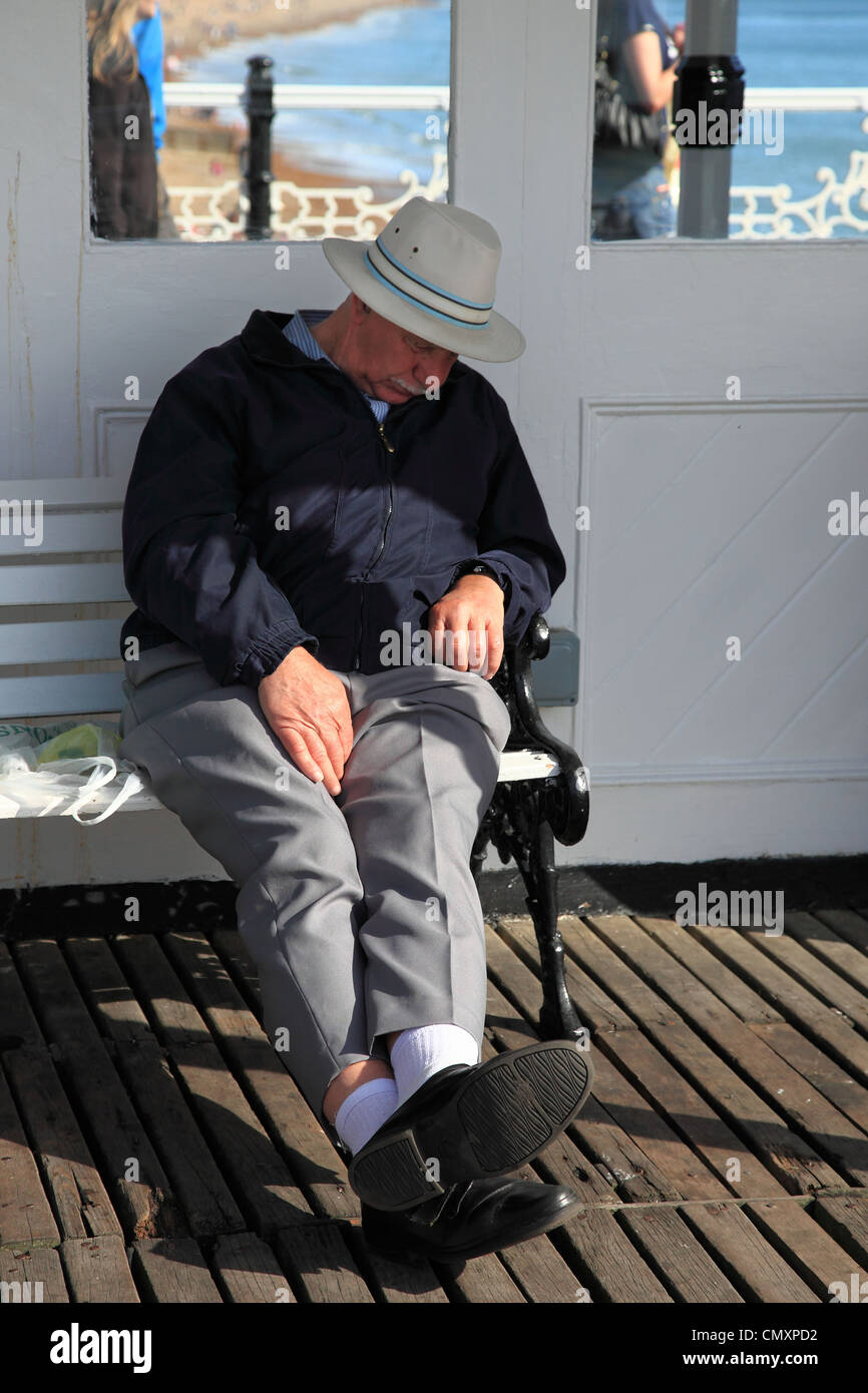 Vieil homme dormir sur la jetée de Brighton, Brighton, Sussex, Angleterre Banque D'Images