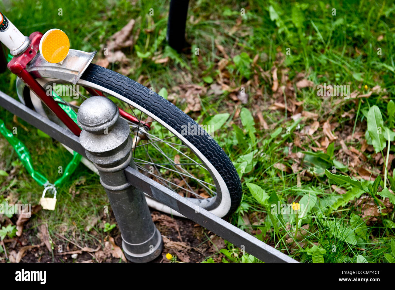 Une photo d'un vélo attaché à un poteau près de l'herbe. Banque D'Images