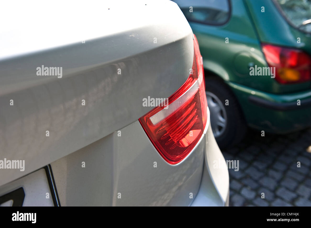 Un angle shot de l'arrière droit d'un livre blanc BMW X6 dans un parking à côté d'une voiture verte. Banque D'Images