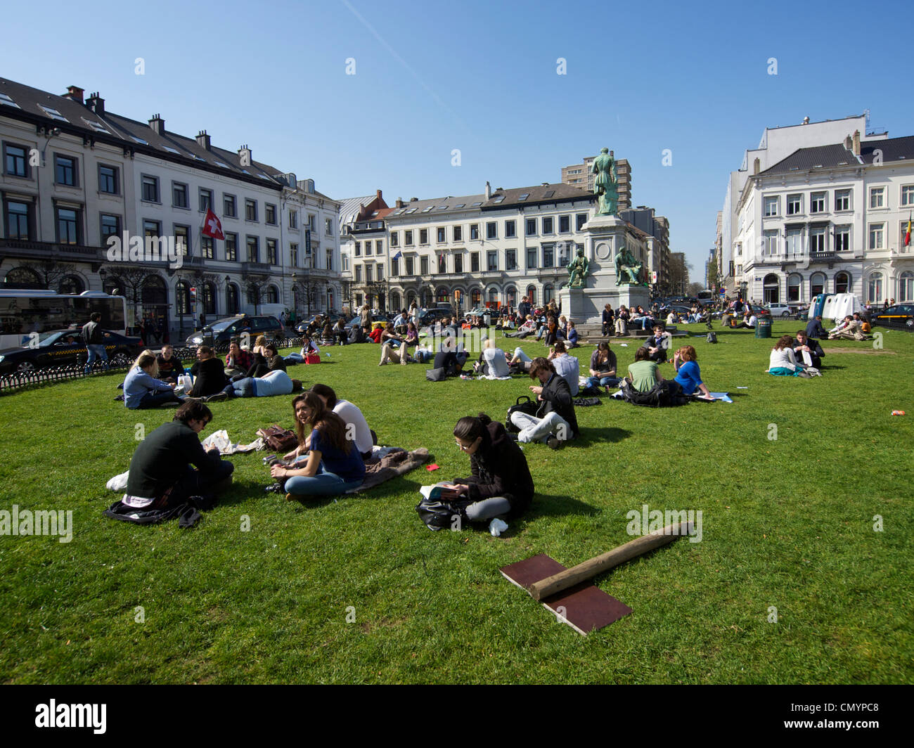 Beaucoup de gens profiter du soleil pendant leur pause déjeuner sur l'herbe de la Place du Luxembourg à Bruxelles, Belgique Banque D'Images