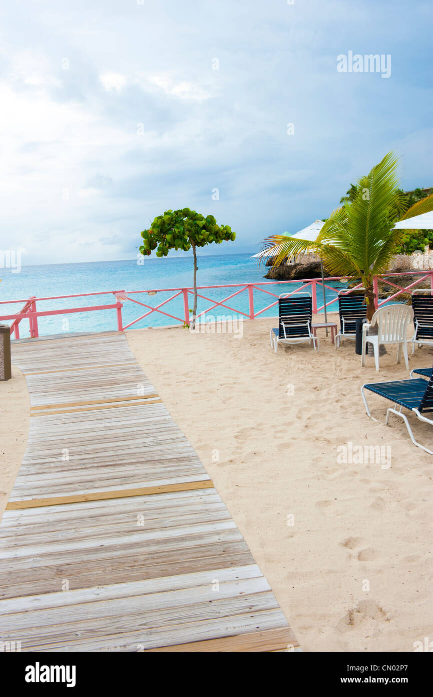 Meubles beach resort entourant une passerelle en bois sur le sable. Banque D'Images
