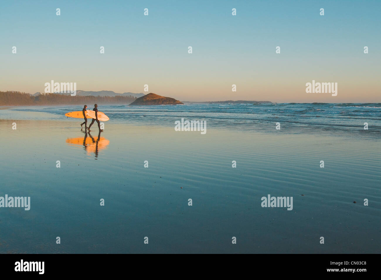 La position de Surfers pour les vagues au coucher du soleil sur la plage de Long Beach, la Réserve de parc national Pacific Rim, côte ouest de l'île de Vancouver, C.-B. Banque D'Images