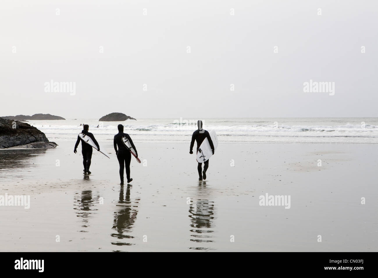 Trois surfeurs à pied sur la plage vers le Surf, Tofino (Colombie-Britannique) Banque D'Images