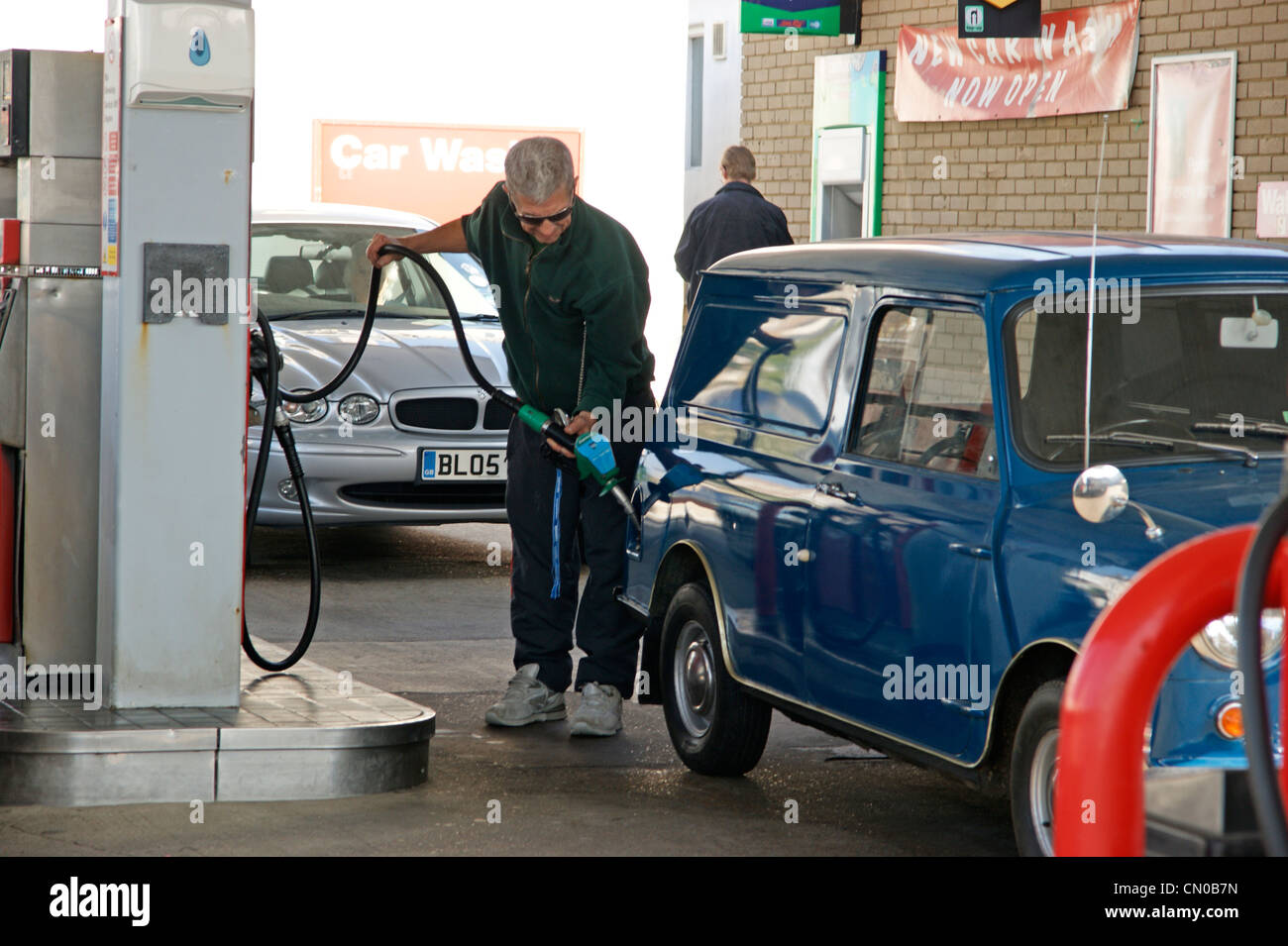 Crise du carburant - l'homme qui remplit sa voiture avec l'essence à une station service Texaco parvis garage voitures d'attente dans la route Banque D'Images