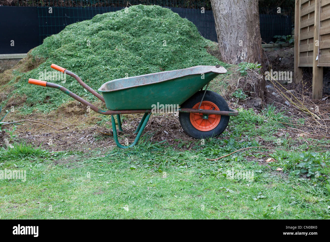 Brouette de jardin en face d'un tas de compost et gazon Banque D'Images