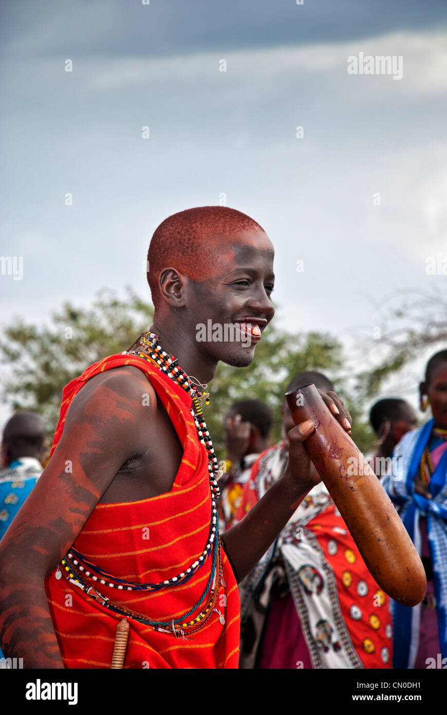 Homme Masai, portant des vêtements traditionnels colorés, de boire le sang de vache une calebasse, un village dans le Masai Mara, Kenya, Afrique Banque D'Images