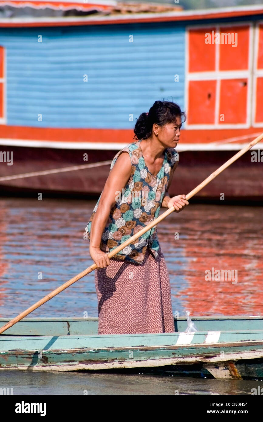 Une femme asiatique est le guidage d'un bateau de pêche longtail sur le Mékong à Luang Prabang, Laos Banque D'Images