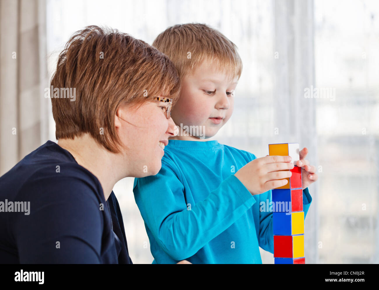 Mère et son petit fils jouer blocs colorés à la maison Banque D'Images