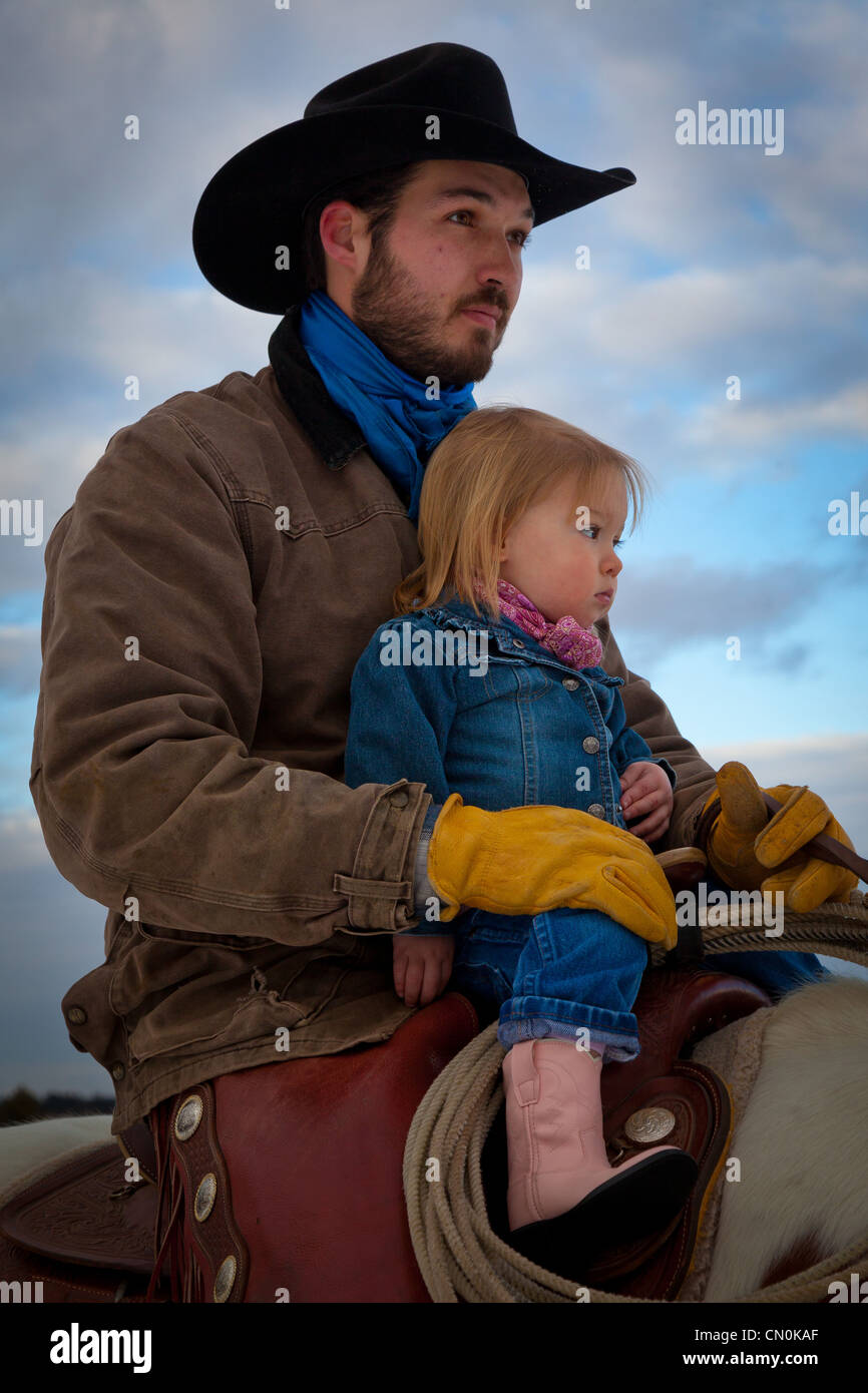 Un cowboy et sa fille à cheval au ranch dans le nord-est du Wyoming Banque D'Images