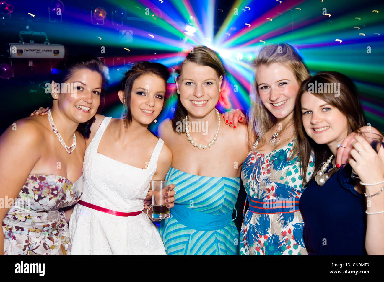 Un groupe de cinq filles s'amuser lors d'une fête ou de nuit avec soirée disco lights dans l'arrière-plan. Banque D'Images