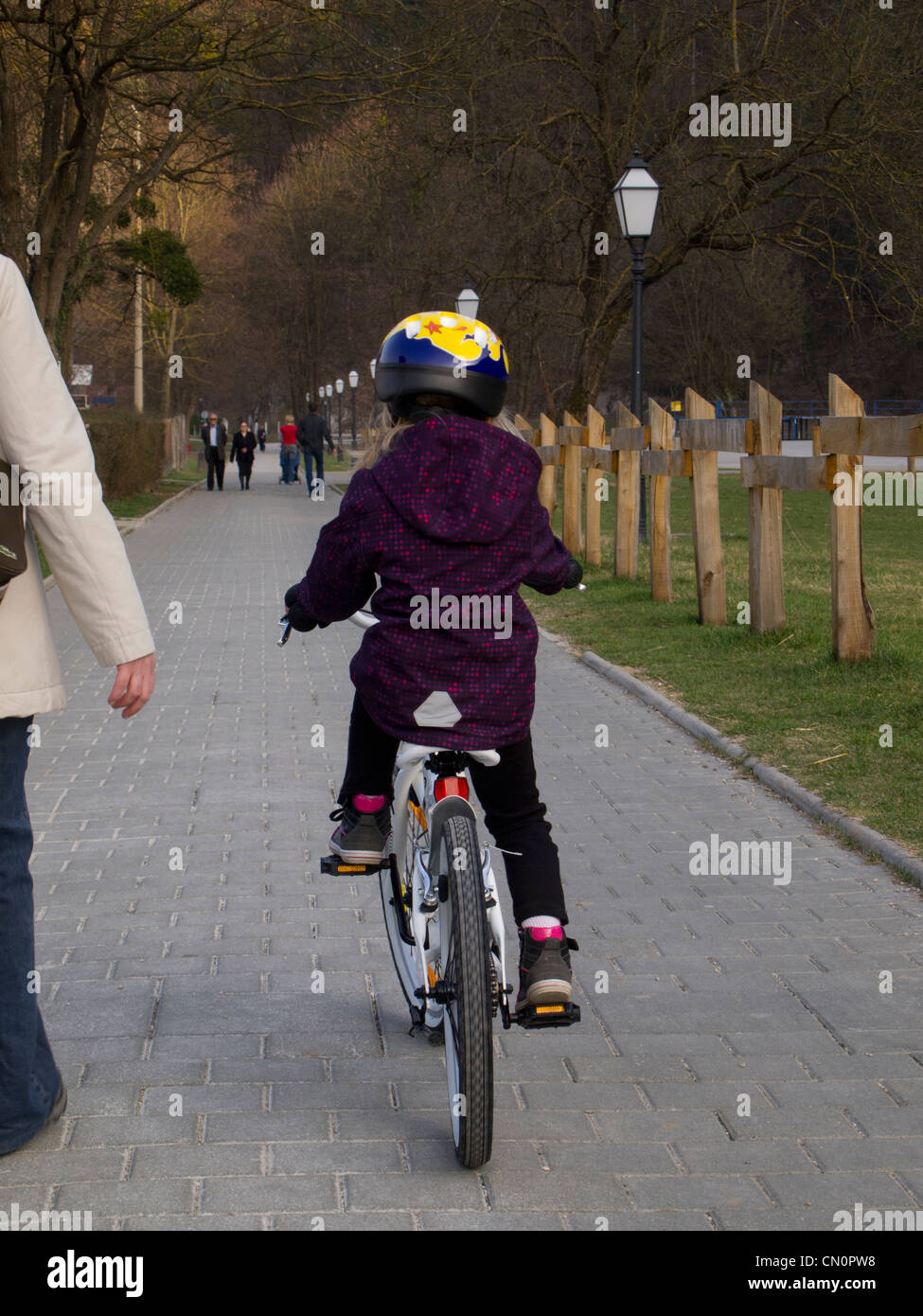 Six ans, fille, et faire du vélo dans un parc de la ville Banque D'Images
