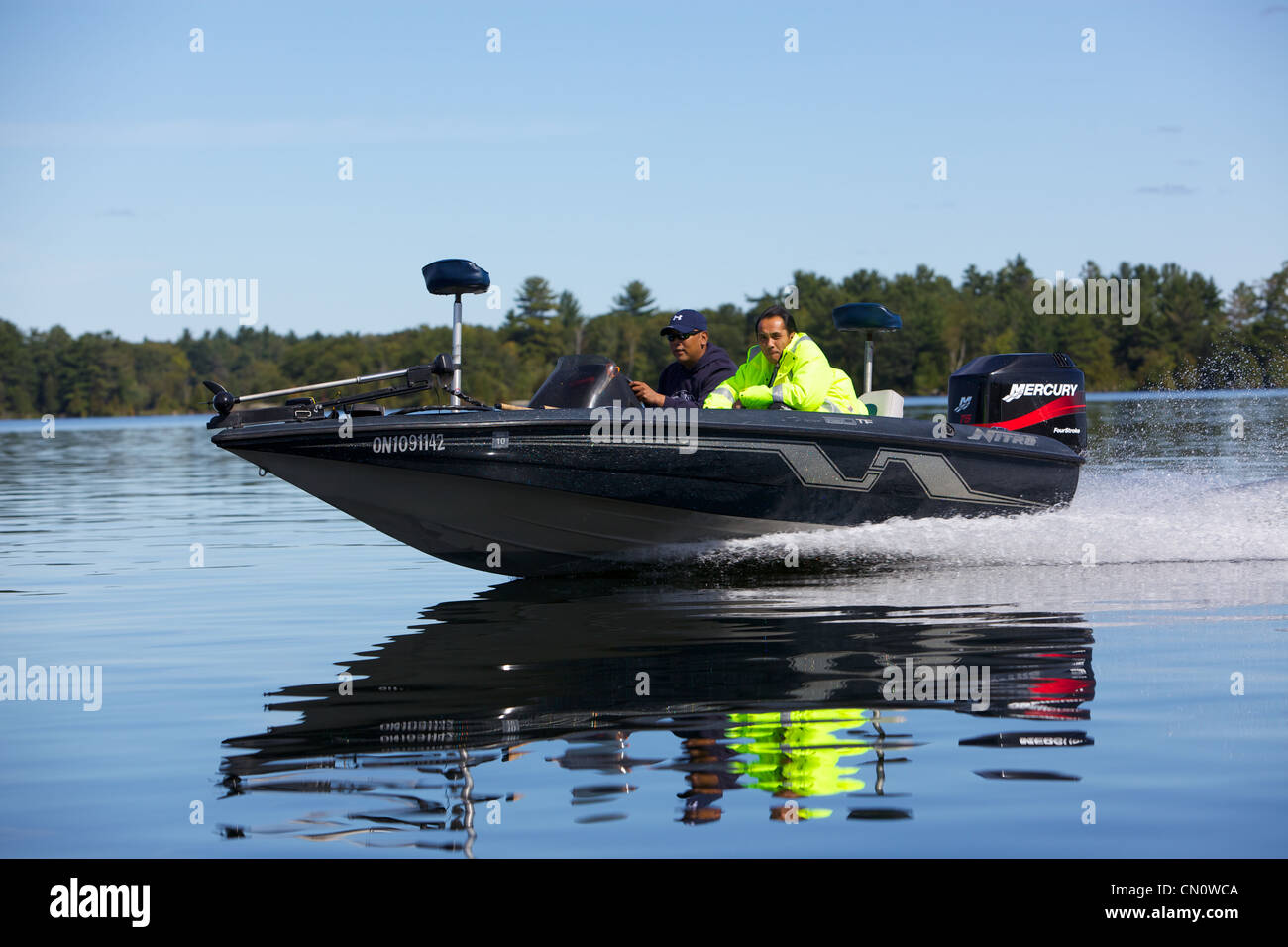 Bass boat gracieusement glisser sur l'eau miroitant. Banque D'Images