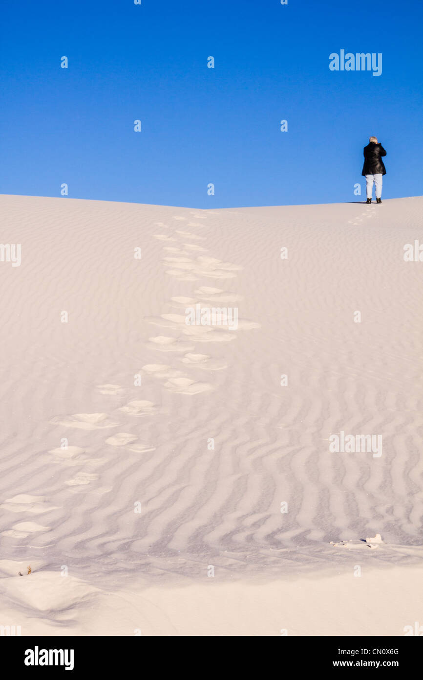 Photographe grimpant des dunes de sable au parc national de White Sands (anciennement Monument national) au Nouveau-Mexique, par une matinée froide en février. Banque D'Images