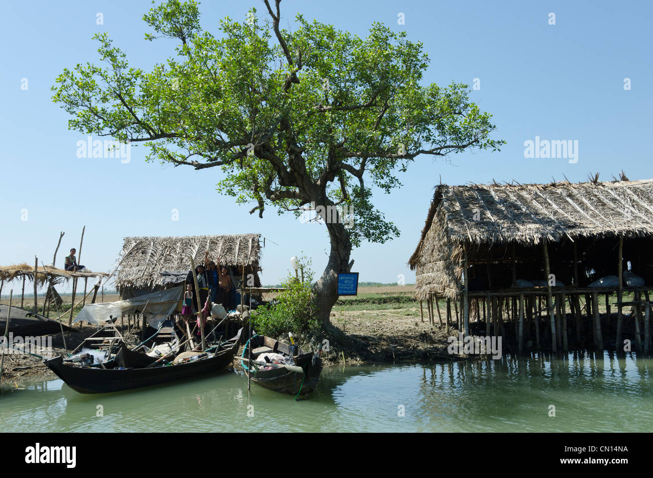 Huttes de bambou et bateaux le long d'une voie navigable. Delta de l'Irrawaddy. Le Myanmar. Banque D'Images