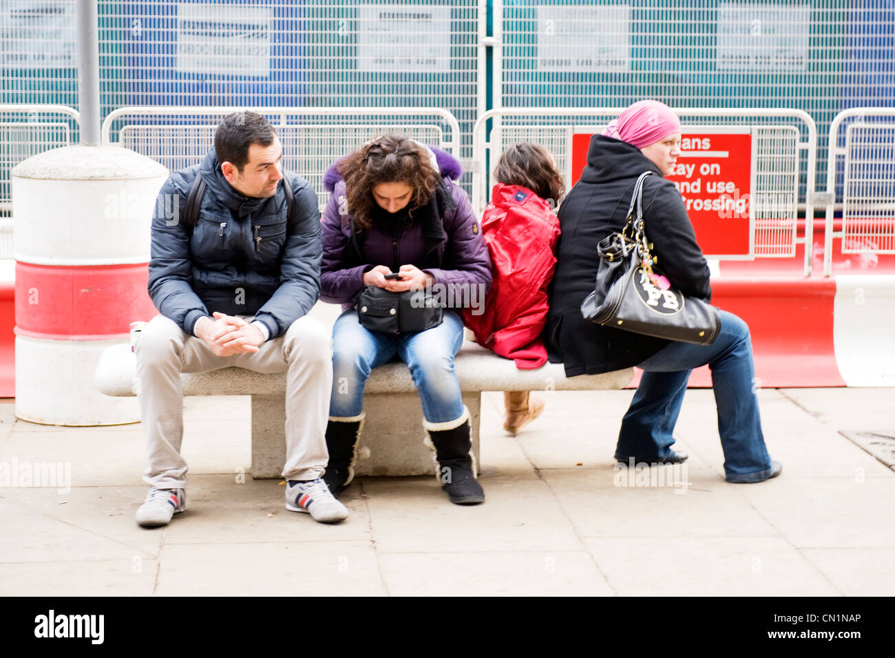 Oxford Street London West End shoppers s'asseoir sur un banc de pierre partager par les travaux routiers femme textos mobile cell phone Banque D'Images