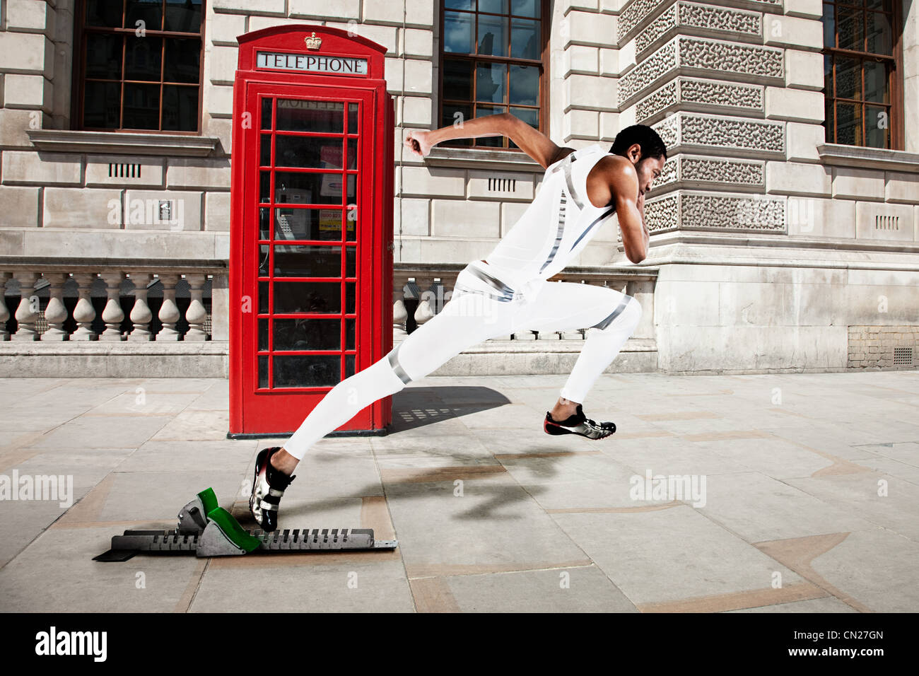 Sprinter olympique sur la ligne de départ avec téléphone rouge fort en arrière-plan Banque D'Images