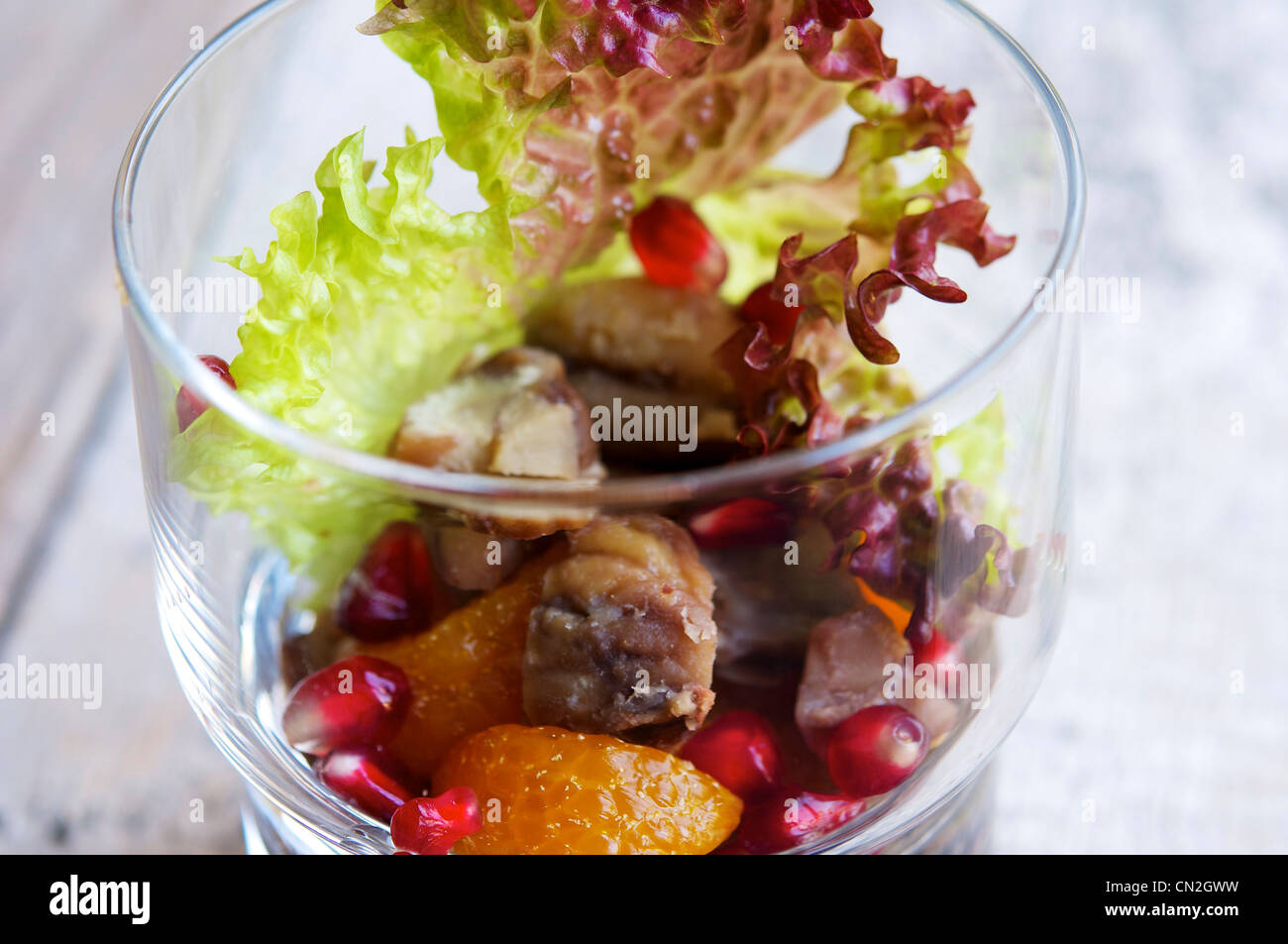 Salade dans un verre parfait avec les châtaignes, les mandarines et les graines de grenade avec une sauce de soja d'érable. Banque D'Images