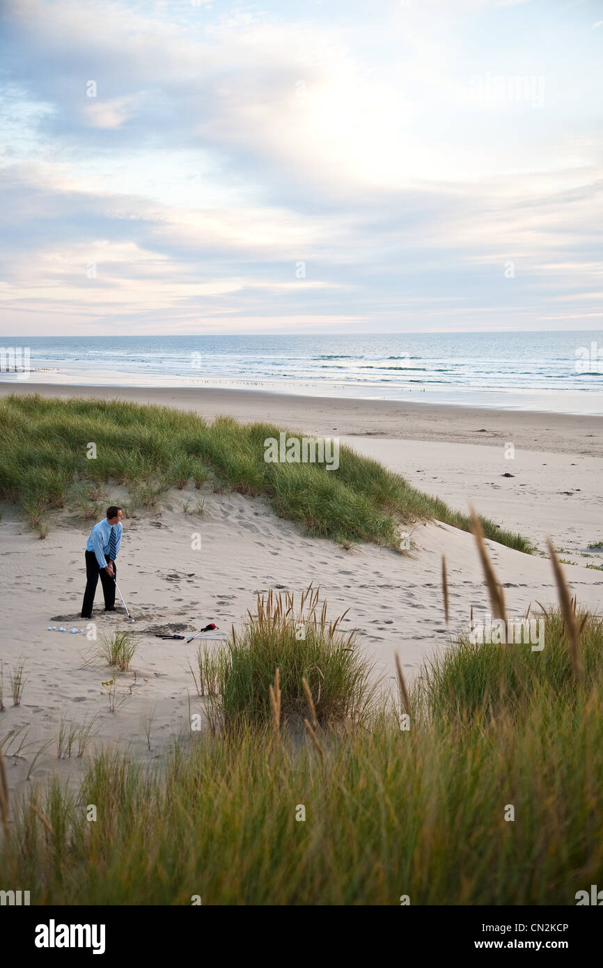 Businessman pratiquer le golf sur la plage Banque D'Images