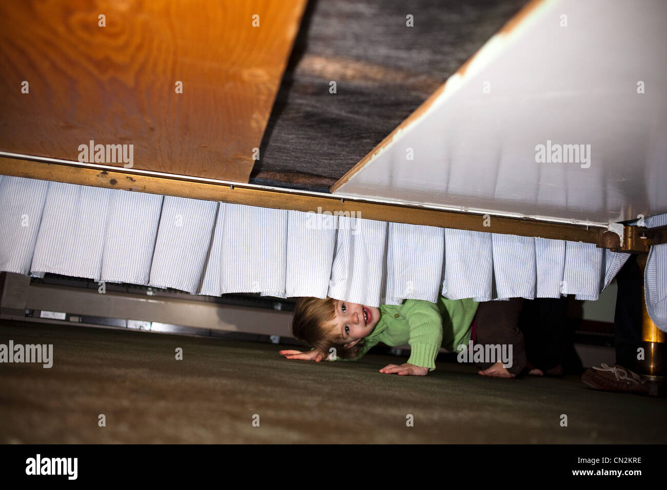 Jeune fille se cacher sous le lit Banque D'Images