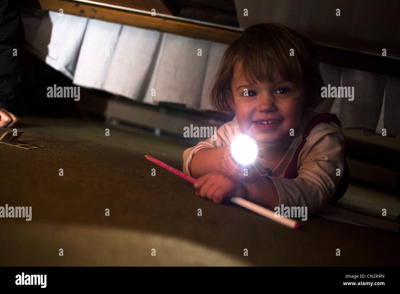 Jeune fille jouant avec une torche sous bed Banque D'Images