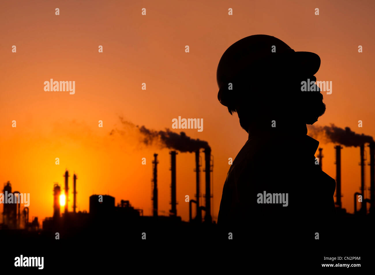 La silhouette de travailleur de la raffinerie de pétrole au coucher du soleil Banque D'Images