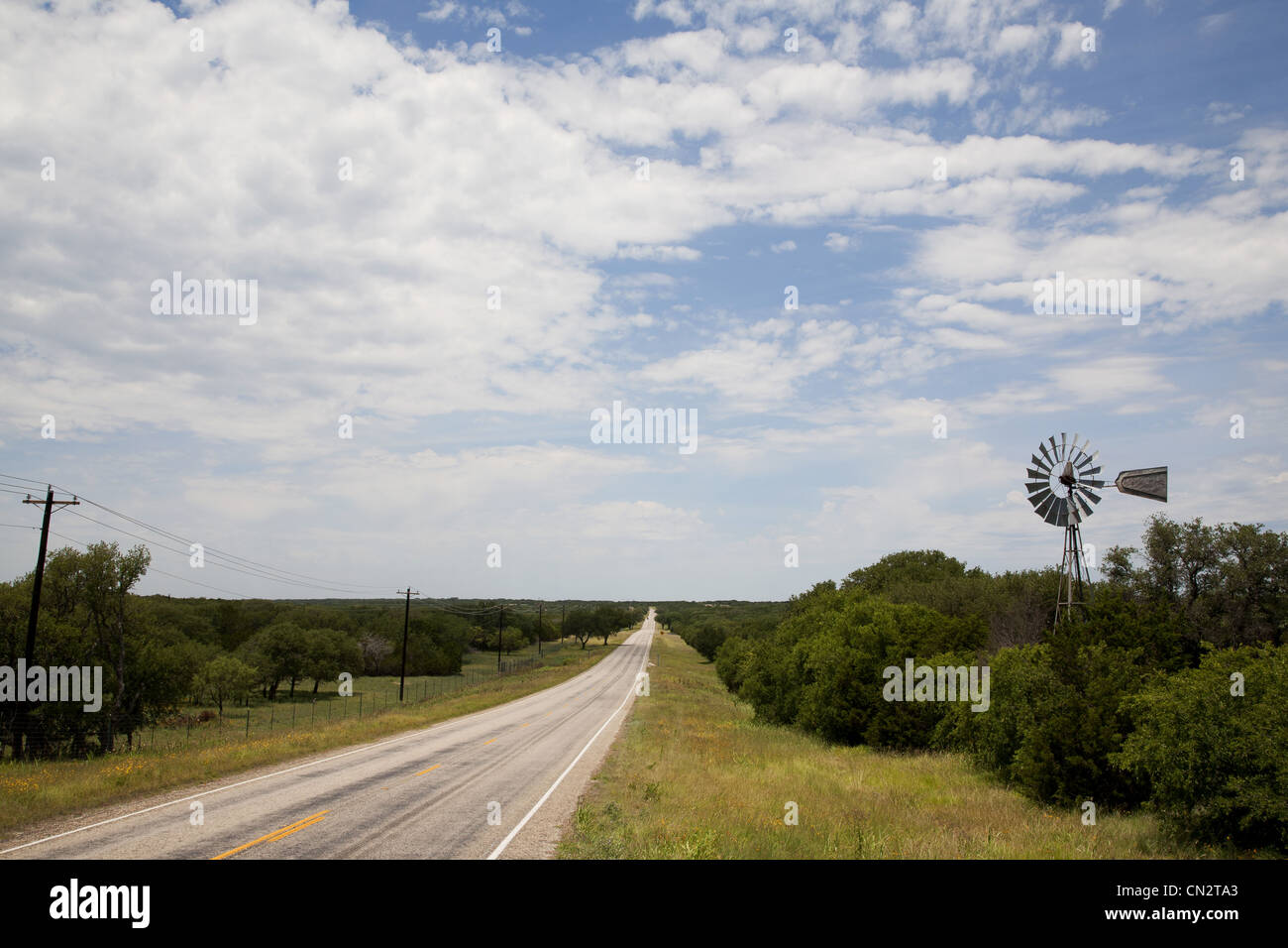 Chemin rural à travers un paysage verdoyant avec Windmill, Texas, États-Unis Banque D'Images