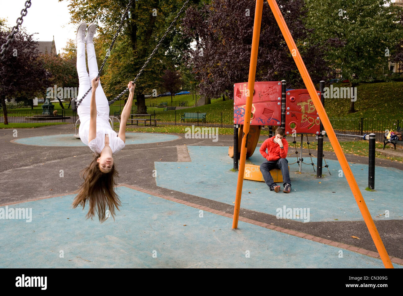 Teenage girl on swing en aire de jeux, à l'envers Banque D'Images