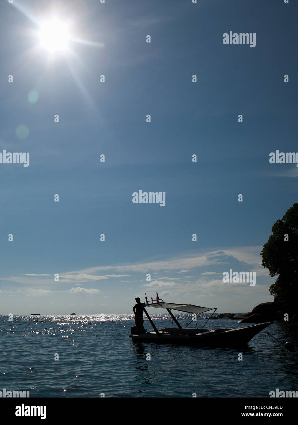 Homme debout sur le bateau amarré dans la lumière du soleil, l'île de Tioman, Malaisie Banque D'Images