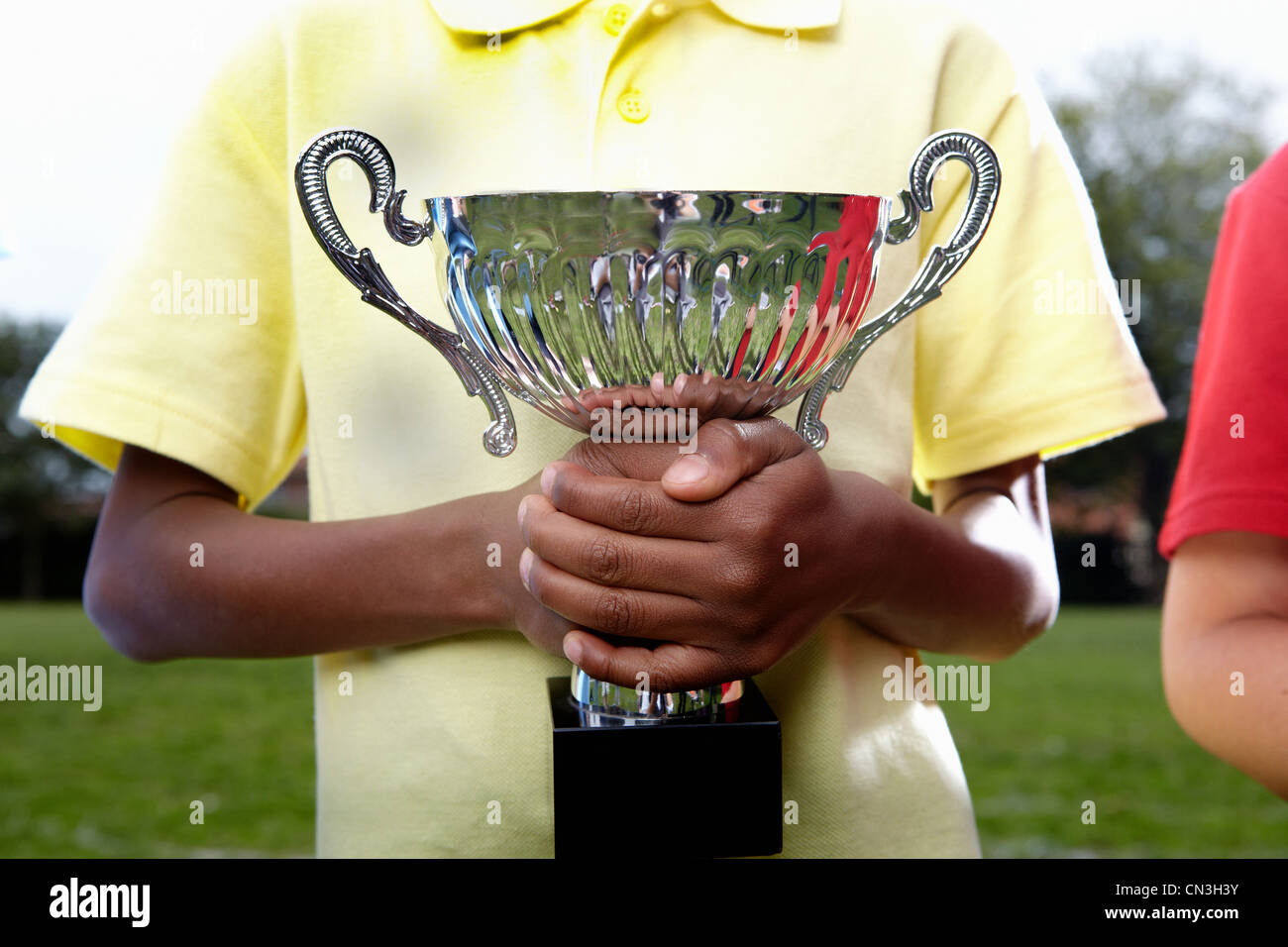 Boy holding trophy cup sur le terrain de jeu de l'école Banque D'Images
