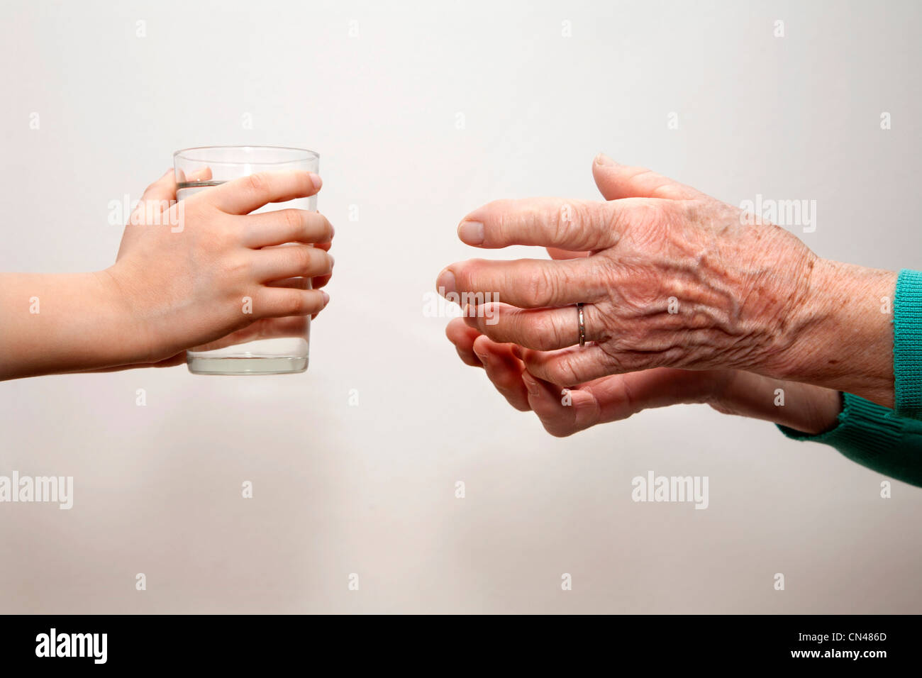 Mains de grand-mère et petit-enfant avec le verre d'eau Banque D'Images