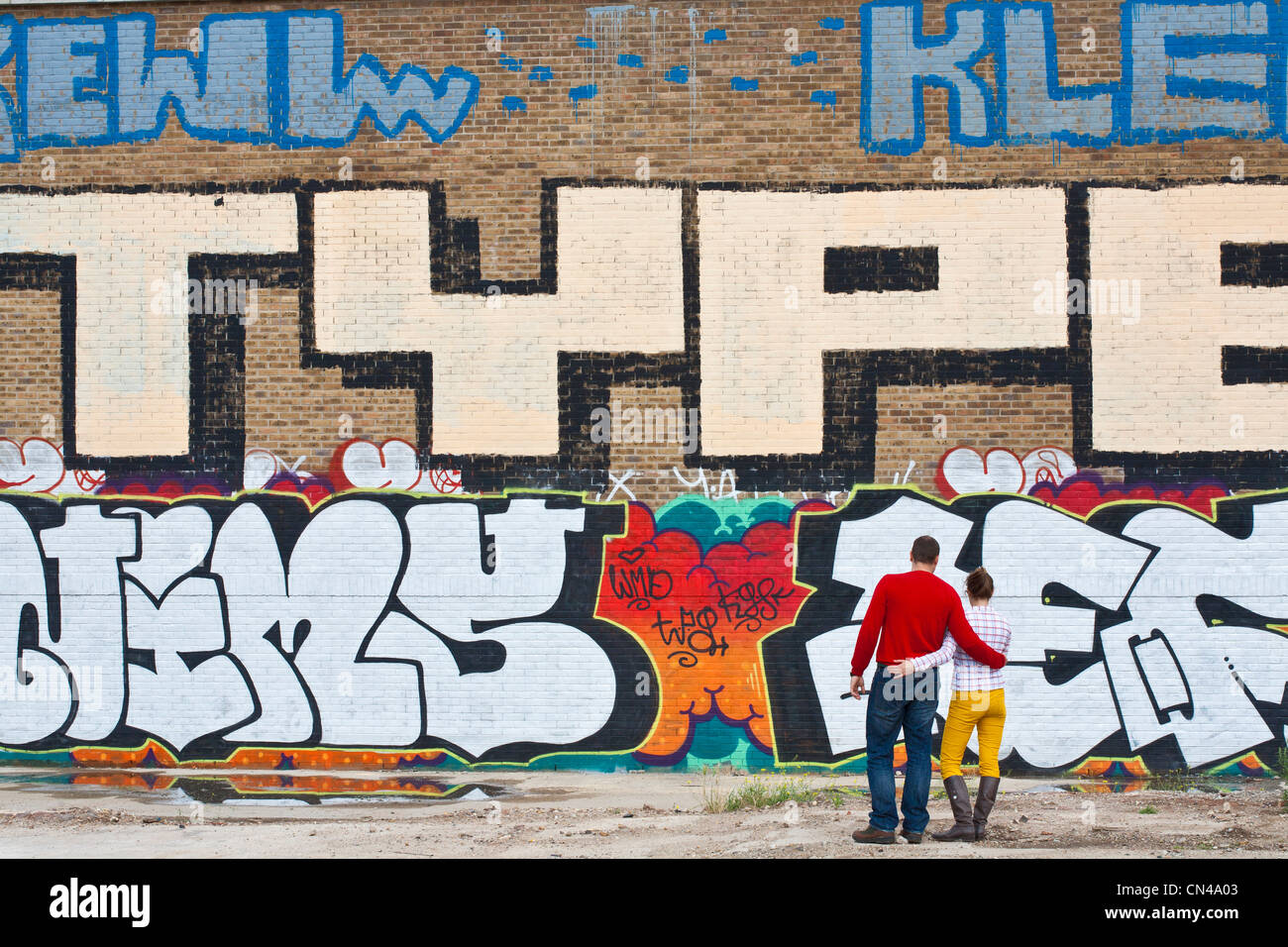 Royaume-uni, Londres, London, Shoreditch, couple en face d'un mur de graffiti Banque D'Images