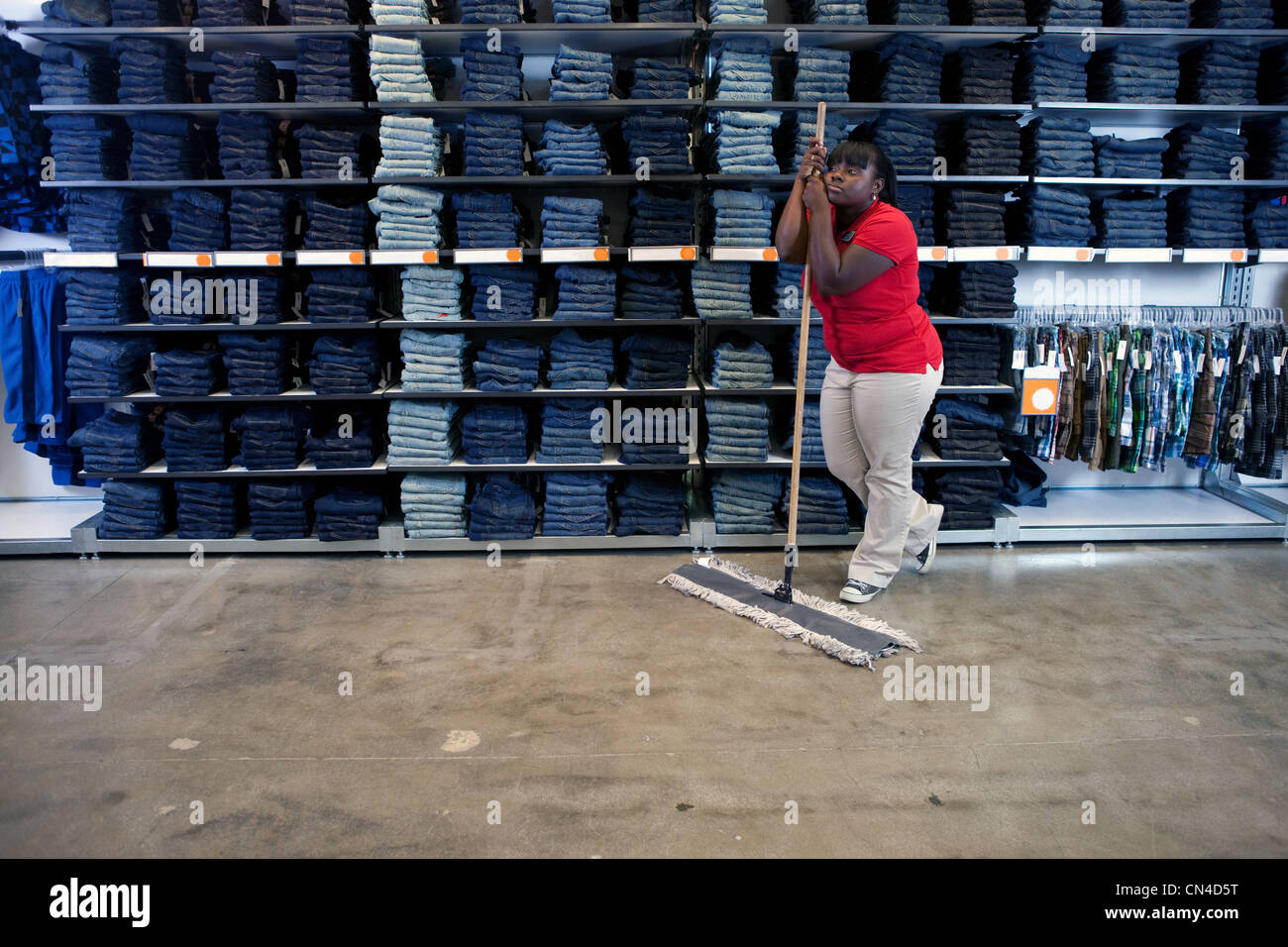 Young woman leaning on balai en magasin de vêtements Banque D'Images
