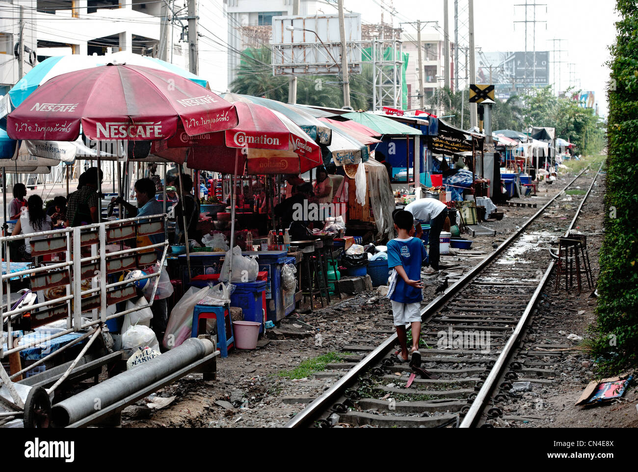 Hawker cale alignées avec le dos à la ligne de chemin de fer dans la région de Nana de Bangkok. Un enfant est de marcher le long du chemin de fer. Banque D'Images