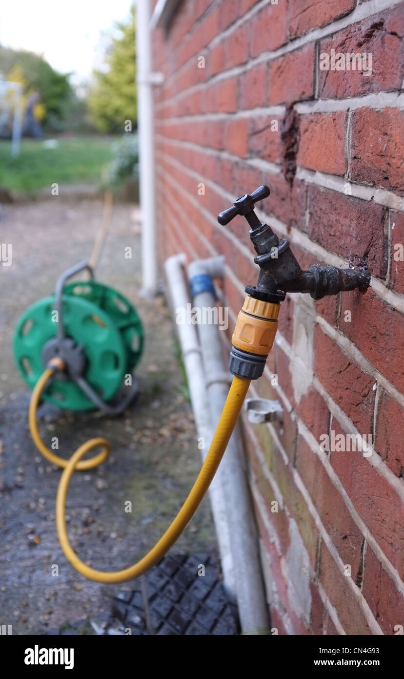 Un tuyau relié à un robinet extérieur pour jardin d'eau Banque D'Images