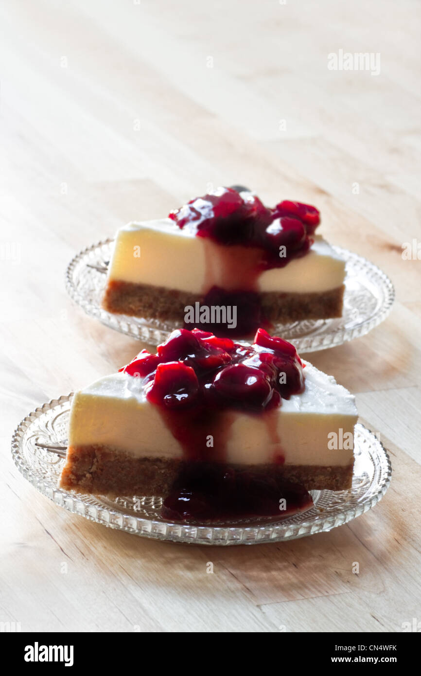 Table en bois avec deux pièces Mon Chou décoré avec la sauce aux cerises tarte sur les soucoupes en verre - vertical image Banque D'Images