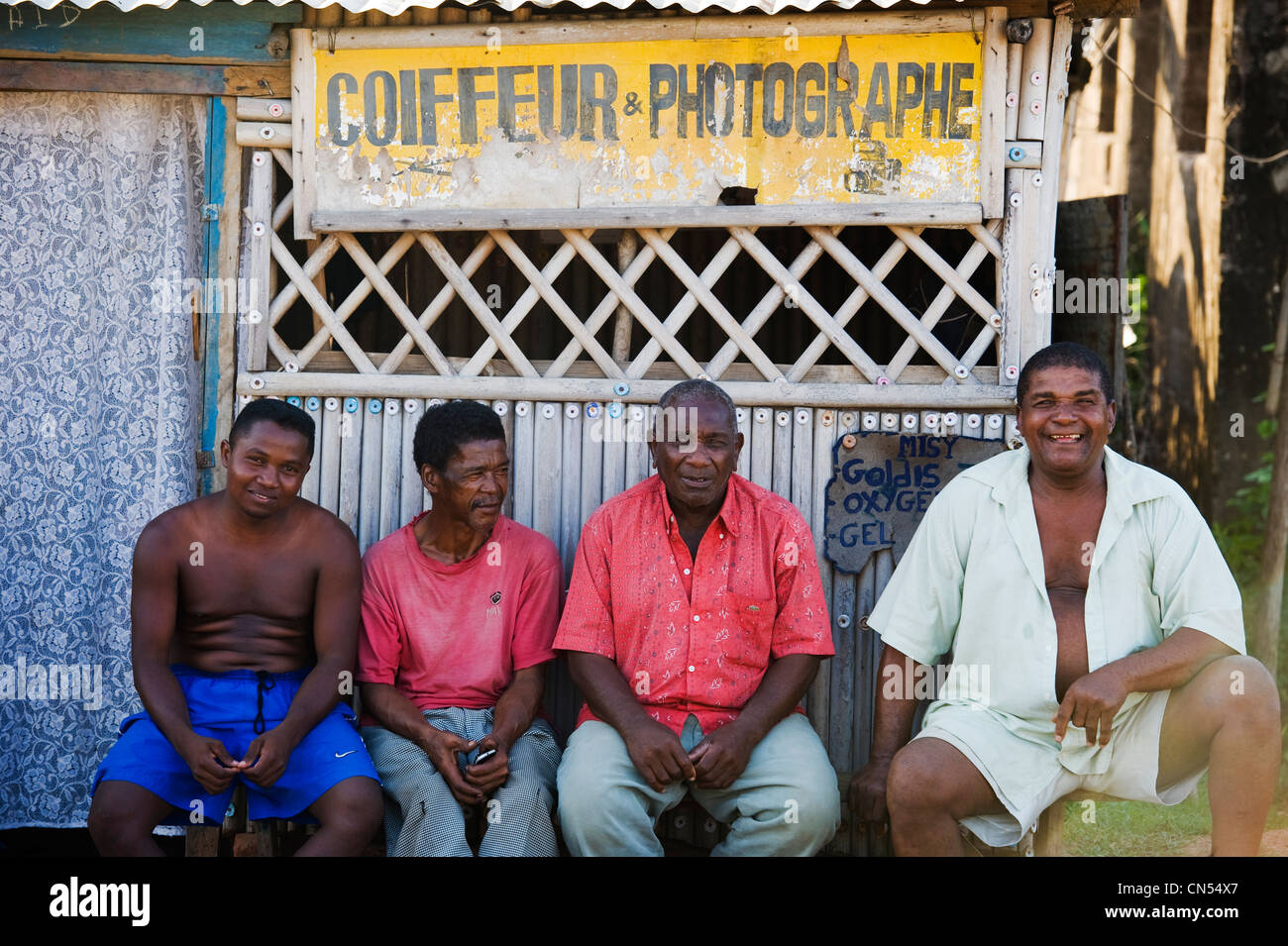 Madagascar, au nord-ouest, ancienne province de Mahajanga (Majunga), région de Sofia, Mampikony, 4 hommes souriant devant un panneau de Banque D'Images